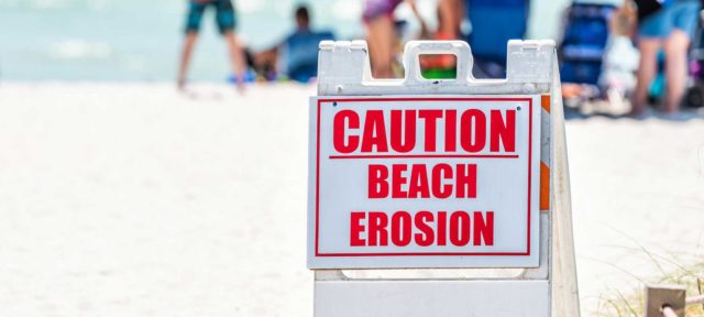 sign on beach saying caution beach erosion