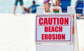 sign on beach saying caution beach erosion